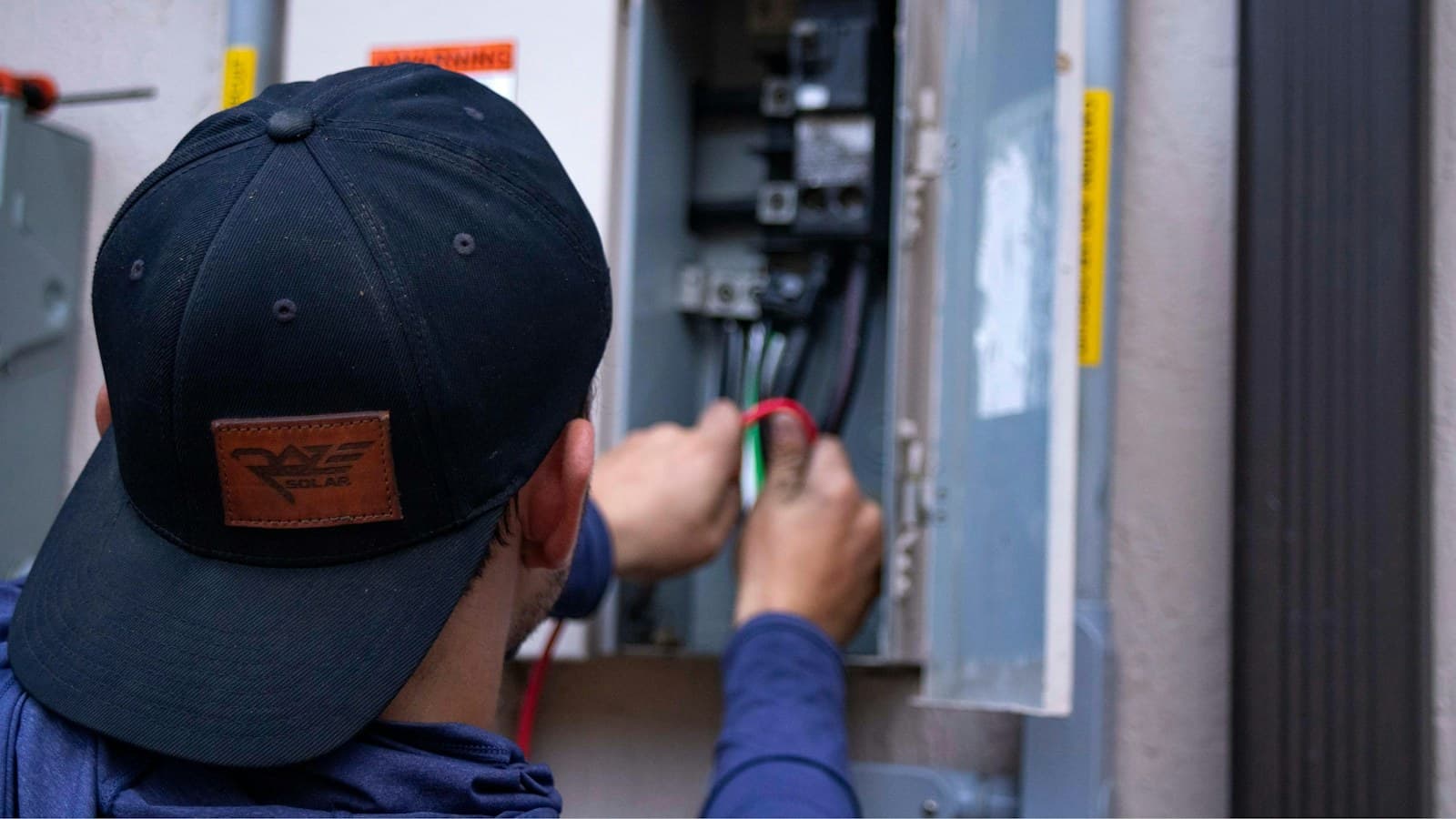 A technician working inside an electrical panel
