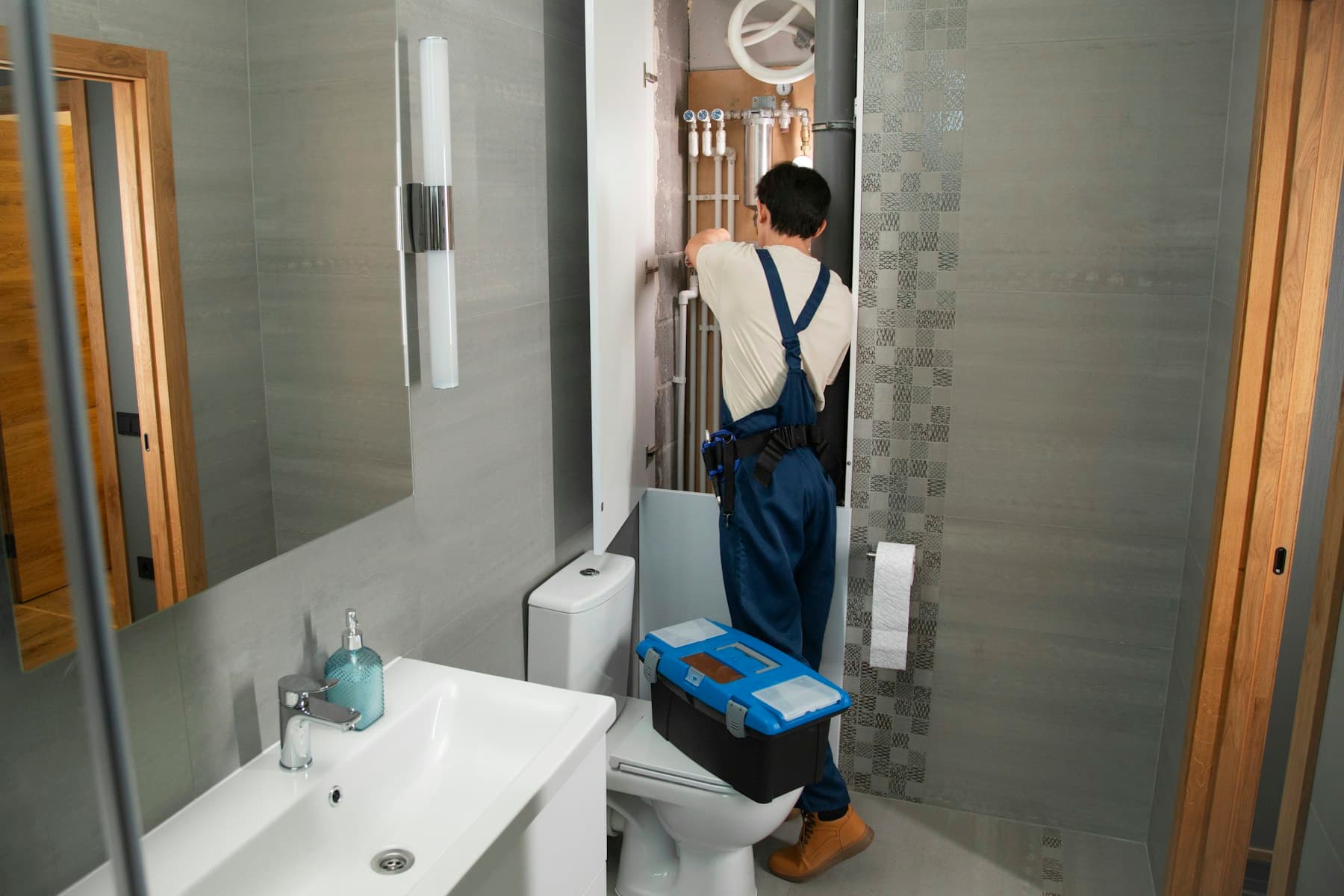 A plumber working on pipes in a bathroom