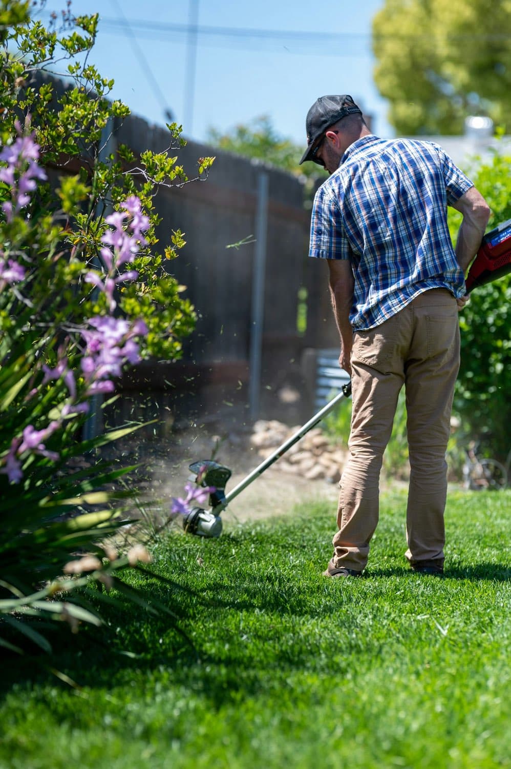 A man trimming a lawn edge with a string trimmer