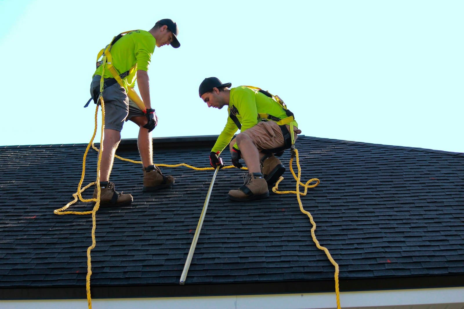 Two roofers in hi-vis shirts working on a shingle roof