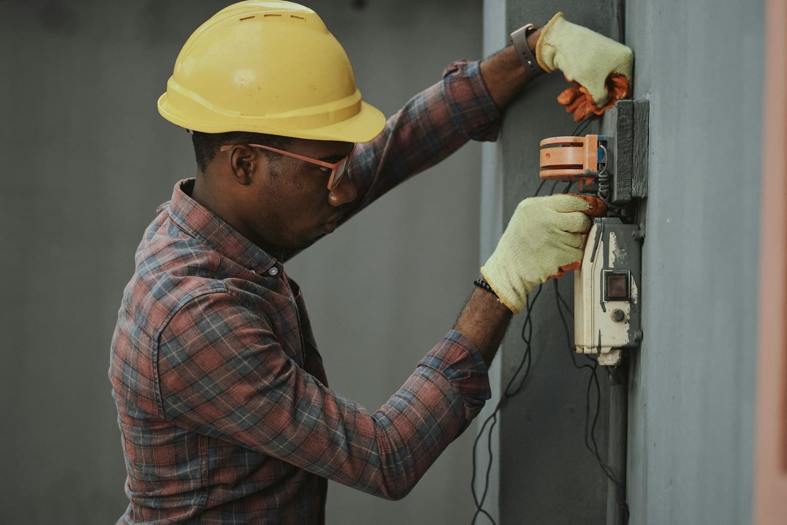 An electrician in a hard hat holding tools