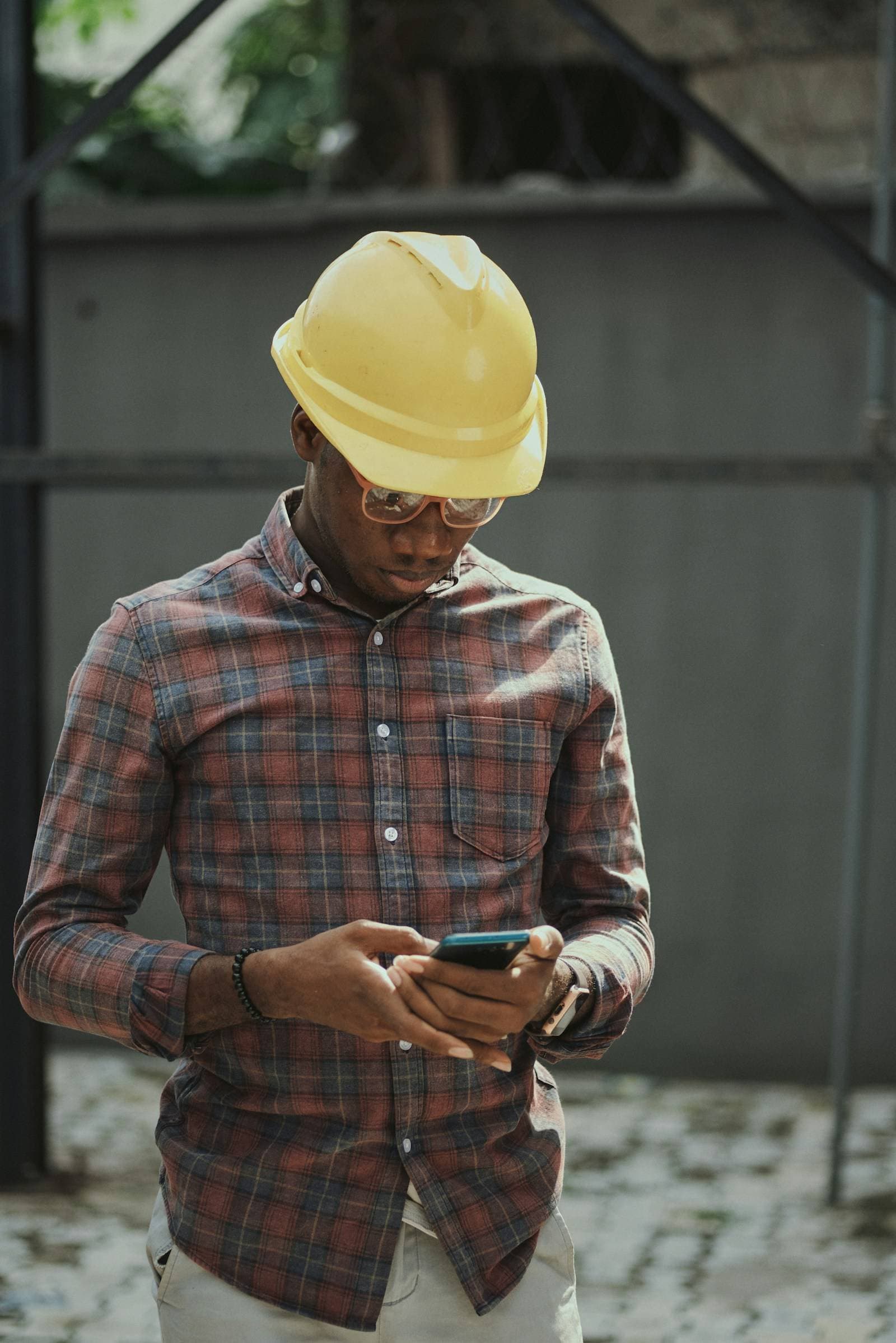 A tradesman in a hard hat checking his phone