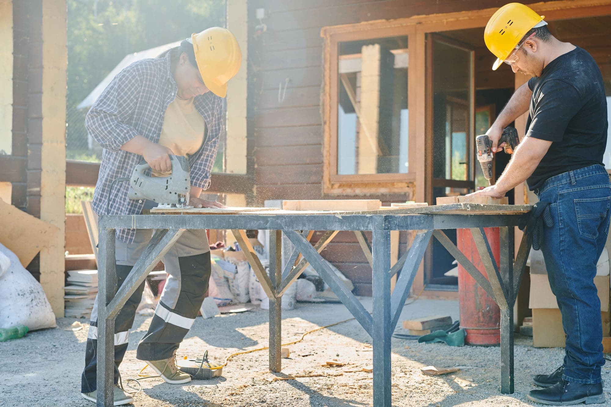 Two workers in hard hats cutting and drilling at a job site